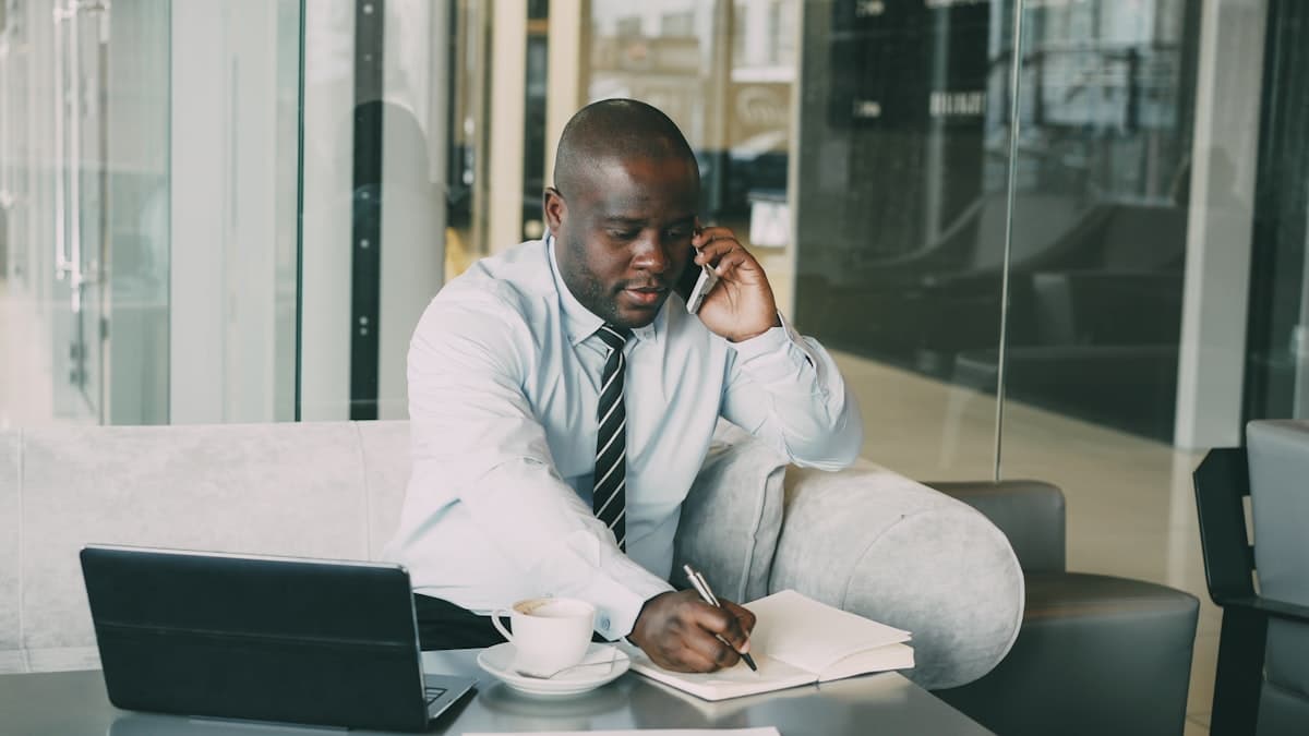 Un responsable au téléphone prend des notes devant son ordinateur portable.