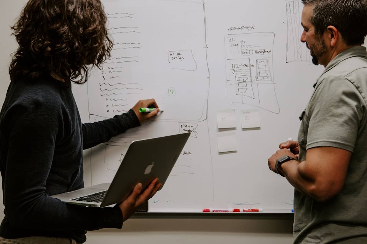 Deux collègues travaillent devant un tableau blanc pendant un atelier d'équipe.
