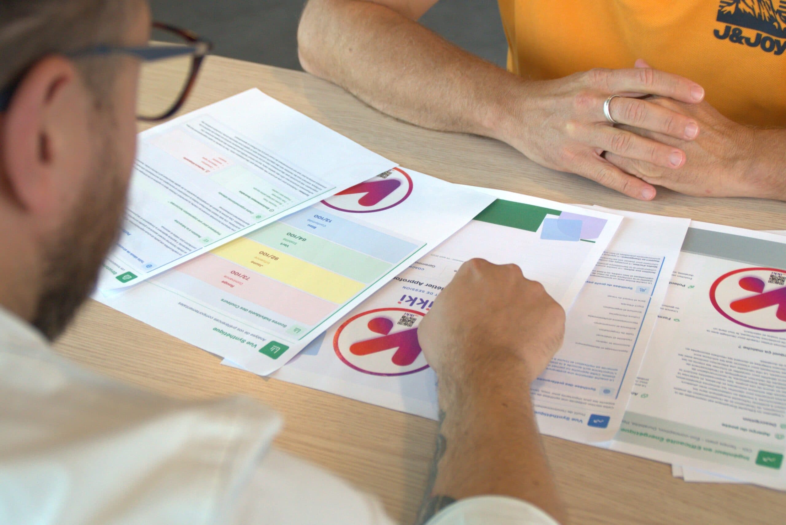 Deux consultants myIKKI examinent des rapports imprimés posés sur la table de réunion.